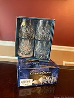 Two sets of four Overture Italian crystal whiskey tumblers shown in original box packaging with blue Overture-branded box below.