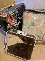 Photo shows three plush blankets in plastic zippered storage bags, with floral and solid color patterns.