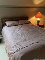 Queen sized bed fully made with pillows, linens, and lamp on side table showing overall bed setup condition