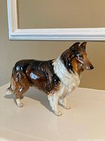 Photo of the Royal Doulton Collie ceramic figurine showing full side profile on a neutral surface with beige background.