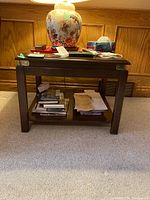 Full front view of the wood top side table showing rectangular shape, dark wood finish, lower shelf with books, and some marks on top surface.