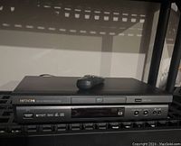 Front view of Hitachi DV-P305 DVD player with original remote placed on top.