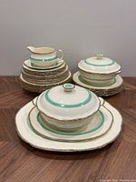 Full view of the entire dinnerware set arranged showing covered serving bowls, gravy boat, plates, and platter stacked.