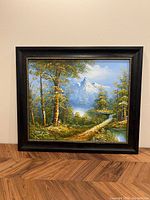 Full view of the framed oil painting showing a landscape scene with trees, a pathway, and a distant snowy mountain under blue sky.