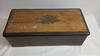 Closed wooden music box with decorative motif on lid