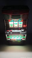 Dark ambient photo showing front of slot machine with illuminated reels and lower panel graphics