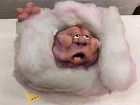 Front and side view of rubber composite sculpture showing face, limbs, and fluffy cloud-like body in white with pink accents.
