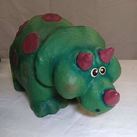 Front angle showing the green dinosaur sculpture with purple horns, nose, and spots.