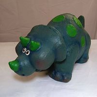 Side and front views of the green and blue dinosaur rubber composite sculpture showing polka dots and horns