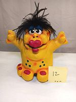 Front view of Creatures of Delight yellow lady monster sculpture with black hair, red lips, and blue spots.