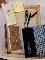 Overview of two Parker Sonnet fountain pens with caps removed and closed Cross pen and pencil set in original box on wooden tray (not included).