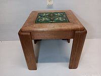 Side view of mid-century solid wood side table showing thick legs and tile inlay on top.
