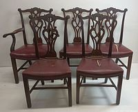 Front view of 5 dining chairs with carved wooden backs and red vinyl seats, one is armchair, four are armless