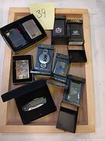 Full lot with two Zippo lighters, cartridges in boxes, keychain, and folding knife lighter in a tray.