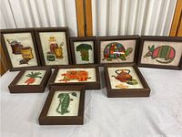 Nine framed embroidered artworks arranged in a group