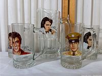 Front view of pitcher and mugs showing colorful Elvis Presley portraits and signatures.