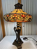 Full view of the Tiffany style table lamp showing stained glass shade and metal base with pull chains.