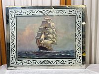 Full front view of the framed print showing the sailing ship artwork and mirrored frame with decoration and visible age wear.