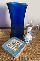 Photo showing large blue glass vase, small clear Dutch-themed vase, and six square coasters with butterfly and botanical designs.