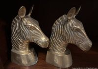 Pair of brass zebra head bookends shown from angled side to display details and shape.