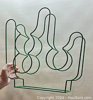 Photo of a green wire wine rack shaped like a cactus with bottle holder holes.