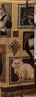 Close-up of a brown shade blanket showing woven images of multiple cats in various frames with a fringed edge