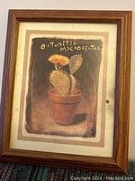 Frontal photo of framed print depicting a flowering Opuntia Macrocentra cactus in a brown pot with a brown wooden frame and white mat. Shows clear view of the brown spot stain on the matting on the right side.