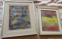 Two framed abstract watercolour paintings, one larger with red, yellow, and blue tones, one smaller with muted colors.