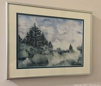 Framed watercolour painting on a wall, showing trees and water with a cloudy sky, matted and in a metallic frame.