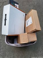 Plastic bin with three cardboard boxes containing various electronics and a Yamaha keyboard on top, items need cleaning