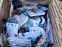 Top-down view inside shipping box filled with many packaged phone holders of various designs including solid colors and soccer ball pattern.