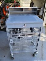 Front view of the gray metal shop desk cart with wire basket labeled 'NON-CONFORMING' and caster wheels.