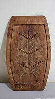 Top view of wooden cutting board with carved geometric leaf design and recessed border