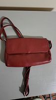 Red leather purse showing front flap and shoulder strap