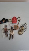 Overall view of assorted keychains including figurines, coin keychain, carved Buddhist piece, and pendant.