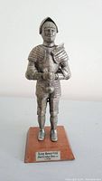 Full frontal view of the pewter figurine of King Henry VIII in foot combat armour on wooden base.