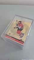 Single Marian Hossa hockey card displayed in protective case showing front with gold background and player in red uniform.