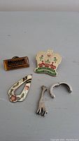 Photo showing five items including pins and silver pieces laid out on a flat surface