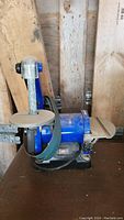 Blue Powerfist belt and disc sander on a wooden surface with sanding belt and disc visible