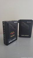 Sony FM/AM Walkman radio cassette player alongside black Sony carrying case