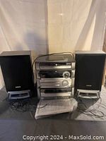 Front view of AWA stereo system including the main stereo unit, two speakers on either side, with manual and antenna cables visible.