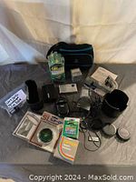 Wide view of all camera accessories spread out on surface showing bags, lens covers, filters, chargers, and cables