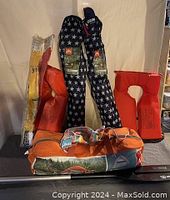 Photo showing two star-patterned inflatable chairs, two orange life jackets, a yellow paddle, and orange tent bag.