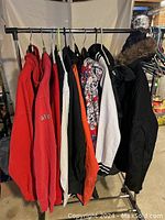 Full view of all jackets and sweatshirts hanging on a rack, showing variety of colors and styles including fur-trimmed and patterned outerwear.