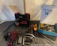 Wide view showing grouped hand tools including screwdriver set, pliers, wrenches, socket handles and heads, multi-tool, and a box with metal hardware.