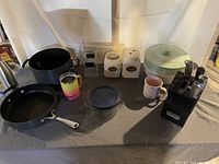 Overview of kitchen items including pot, pan, cups, canisters, bowl, knife block, and containers.