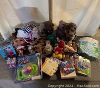 Full view of the lot with plush animals, Beanie Babies, and various toys and games spread out on a surface