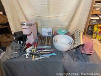 Photo showing assortment of kitchen tools including pink Keurig coffee maker, bowls, utensils, and slicers on a table