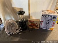 Lot overview showing all four appliances: Gourmia air fryer in box, Farberware fan heater, Hamilton Beach blender, and Waring hand mixer in box.