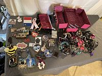 Wide view of lot showing jewelry box, assorted jewelry, makeup holder, and magnets spread on table
